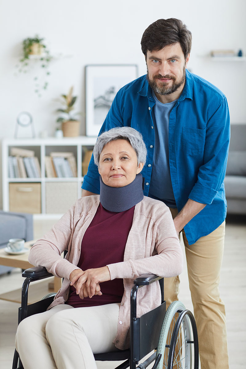 Portrait of mature bearded man caring about disabled senior woman in wheelchair at home